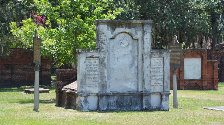 A large gravestone on the grass with trees around it