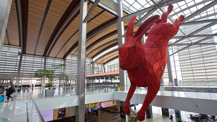 A hanging art deco art piece shaped like a rabbit inside a modernist building