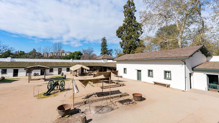 A courtyard with artifacts surrounded by brown-roofed, low white buildings and trees