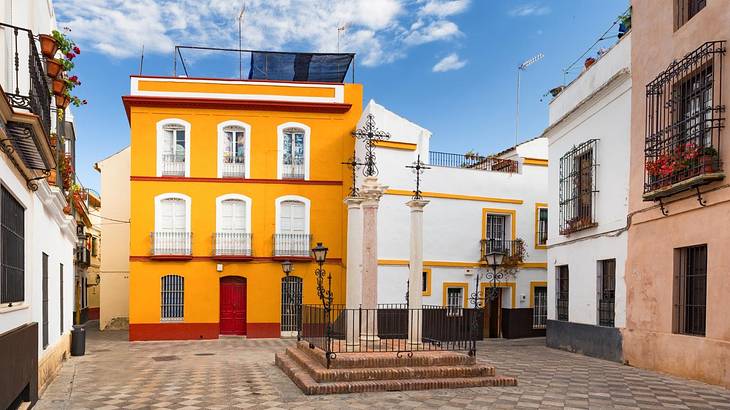 A yellow building in a square with other old buildings around it