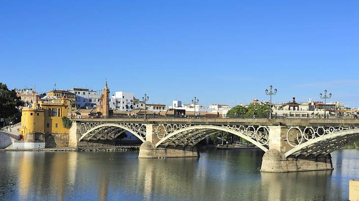 A bridge with three arches over a river with buildings and trees to the side