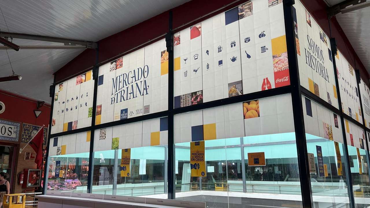 A glass cube with posters and a Mercado de Triana sign on it