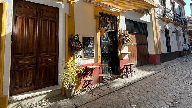 A quaint cafe entrance with some patio tables out front on a cobblestone street
