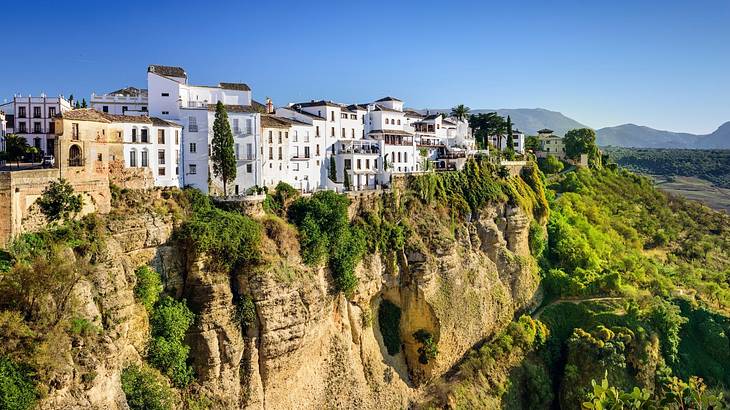 White buildings sitting on a hill covered in greenery, under a blue sky