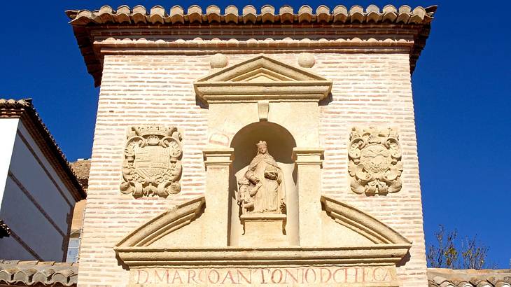 A sculpture of the Virgin Mary carved into a white brick building