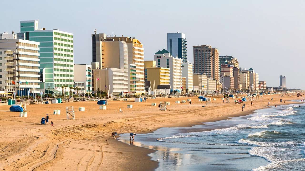 A beach with sandy shores and ocean water next to tall buildings