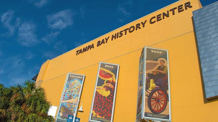 A yellow building with banners and a sign that says "Tampa Bay History Center"