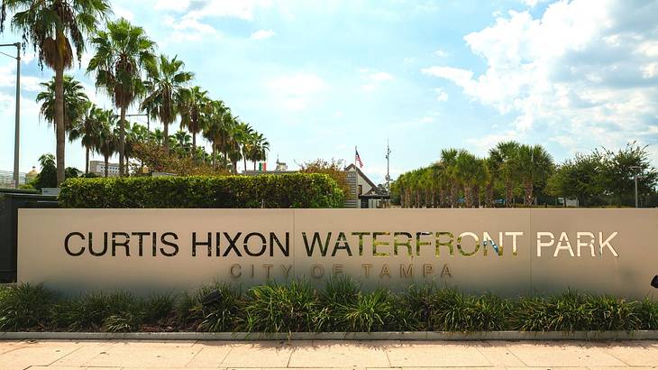 A sign that says "Curtis Hixon Waterfront Park, City of Tampa" next to palm trees