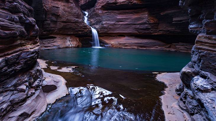 A waterfall flowing into a pool in between rocks, Karijini National Park, Australia