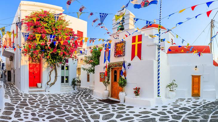 White houses with colorful doors, roofs, and flags along cobblestone streets
