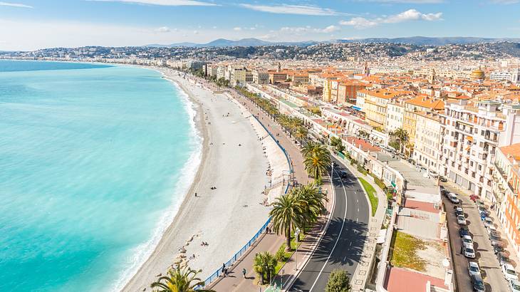 An aerial shot of a city with buildings and roads by the beach