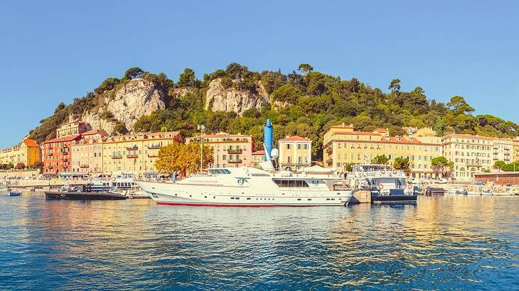 A sea with yachts by an island with colorful buildings and a mountain