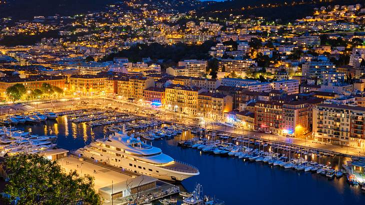 Yachts and boats moored by an inland port in a city full of buildings at night