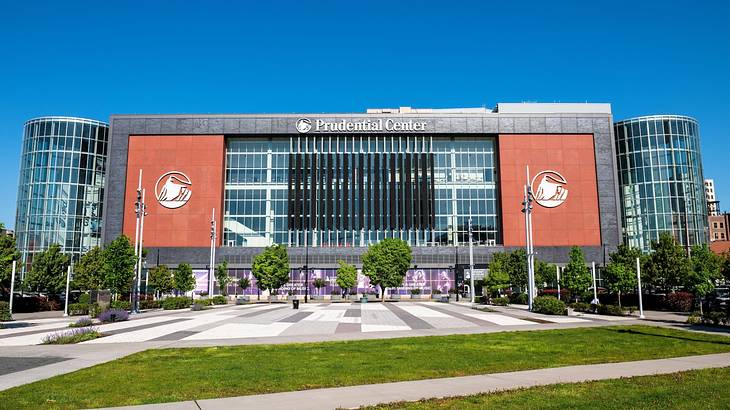 A large building with glass windows and a "Prudential Center" sign next to the grass