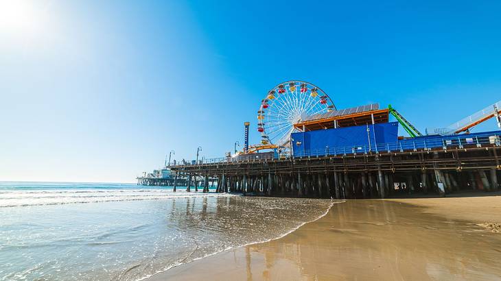 A seaside pier with a Ferris wheel under a sunny sky