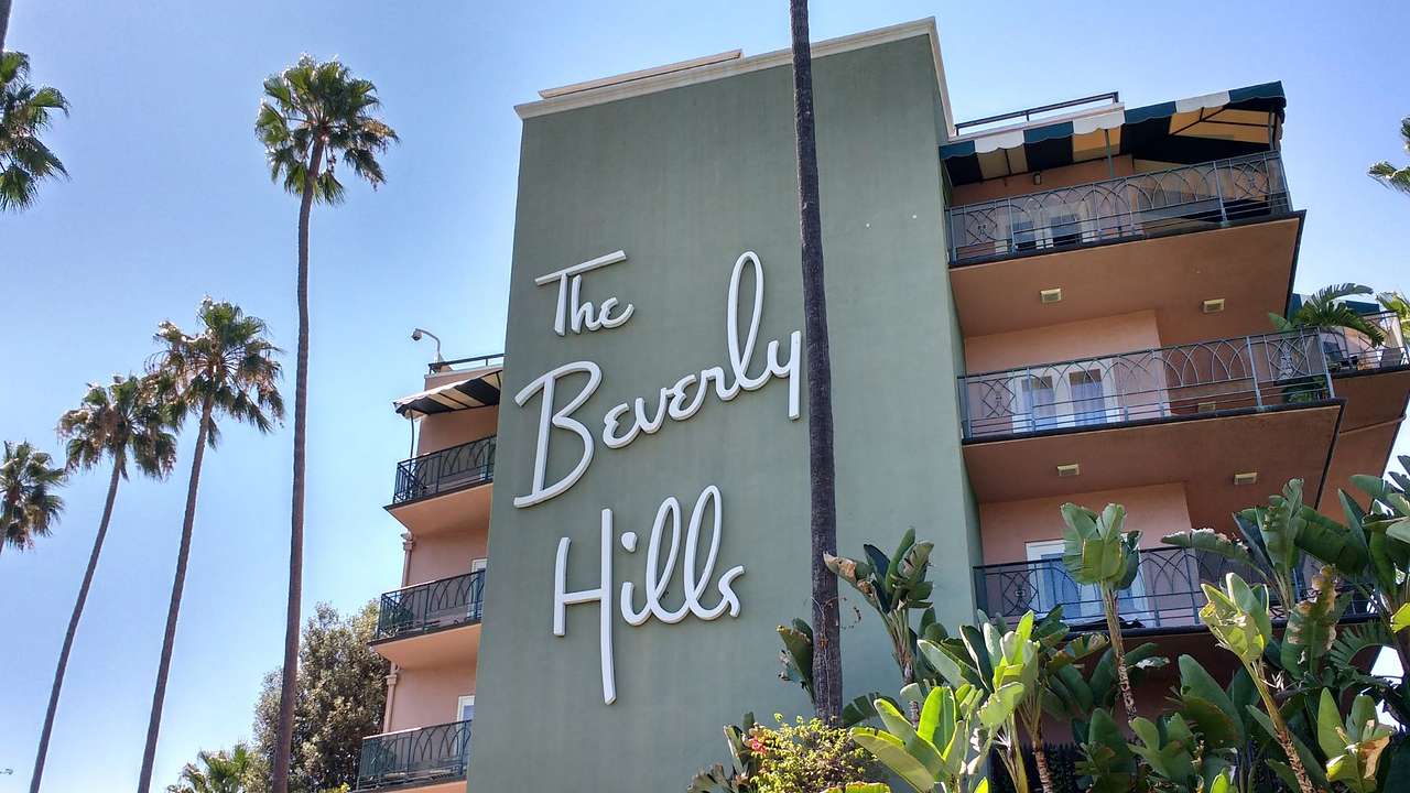 A building with a large sign that says "The Beverly Hills" next to green plants