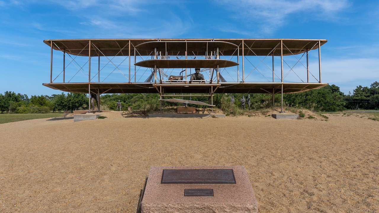 A model of an old-fashioned airplane on the sand with a plaque in front of it