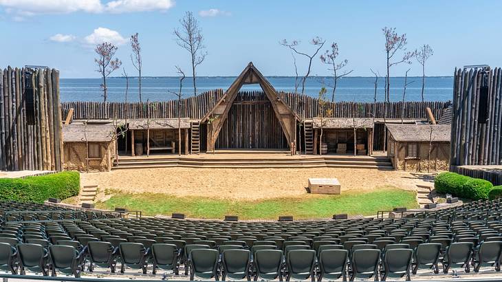 A wooden outdoor theater with seating in the foreground and the ocean behind