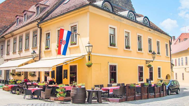 A building with a red, white, and blue flag and outdoor seating around it