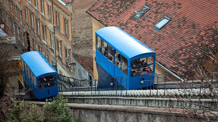 A pair of blue tram cars on a steep funicular railway