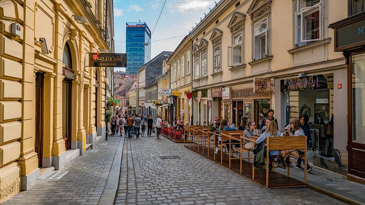 A cobblestone street with restaurants and cafes on one side