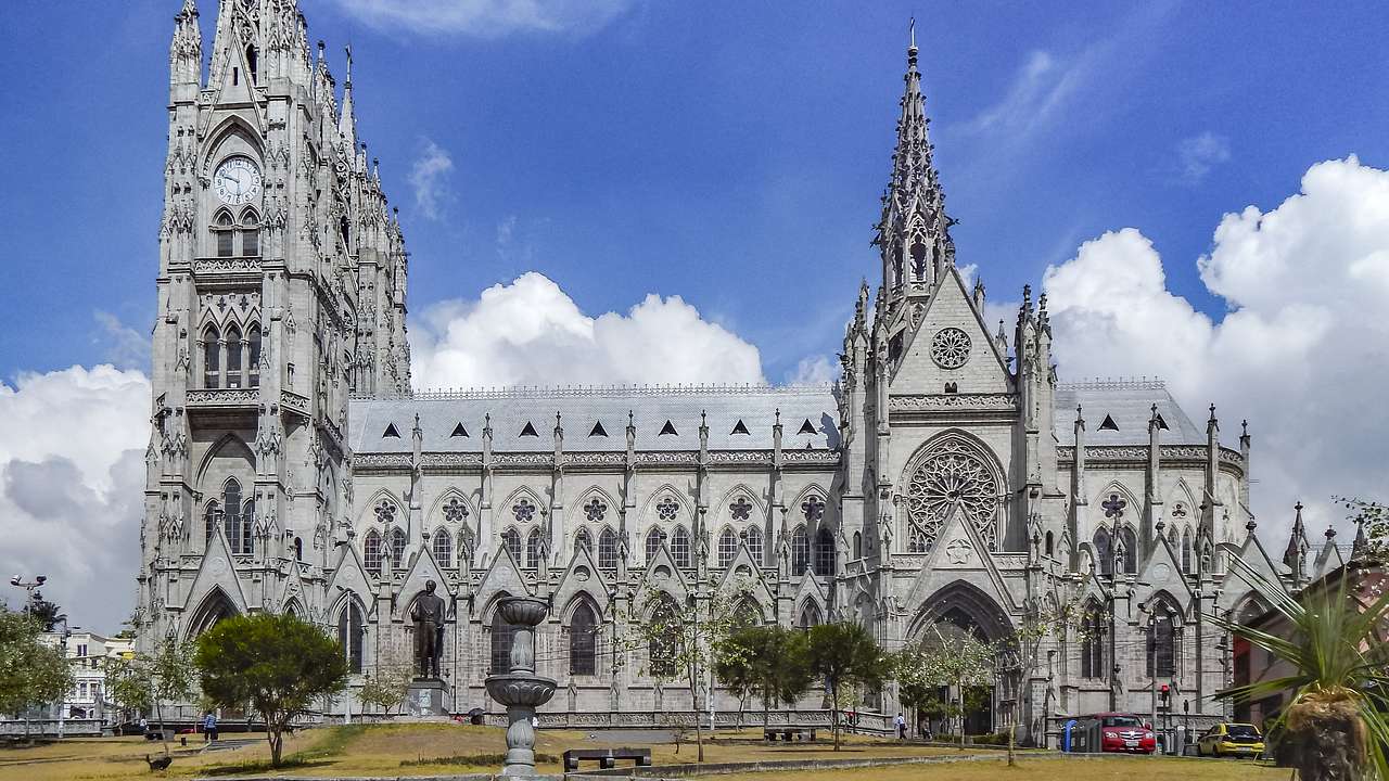 A basilica with stone carvings and towering spires under the blue sky and clouds