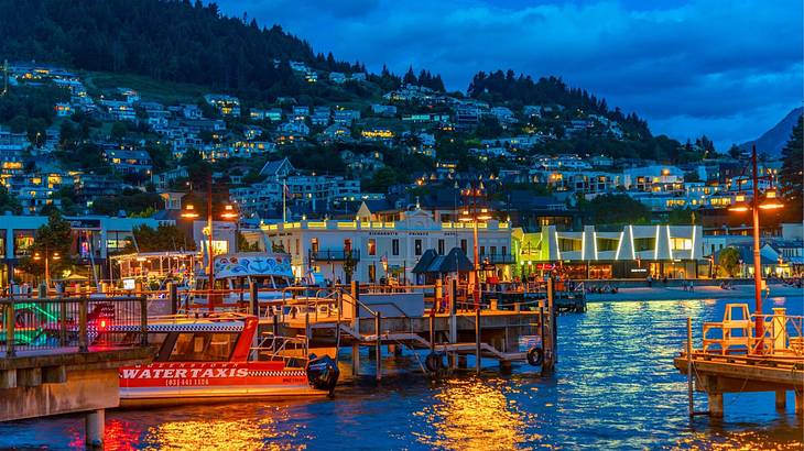 Illuminated houses and establishments situated beside a lake at dusk