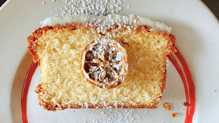 A pastry with orange edges, a dried lemon centerpiece, and a powdered sugar garnish