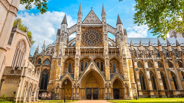 A golden Gothic church with arched doors and windows beneath the blue sky