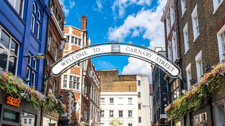 An arched sign over a street that says "Welcome to Carnaby Street"