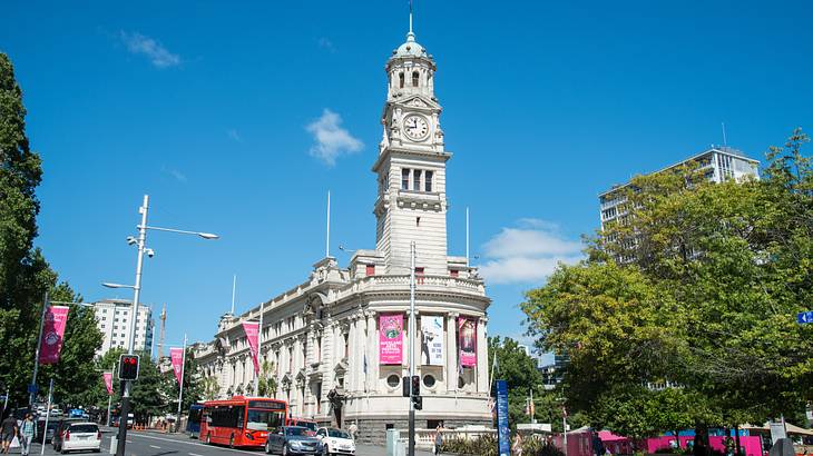 A corner structure building with a clock tower near a road with vehicles