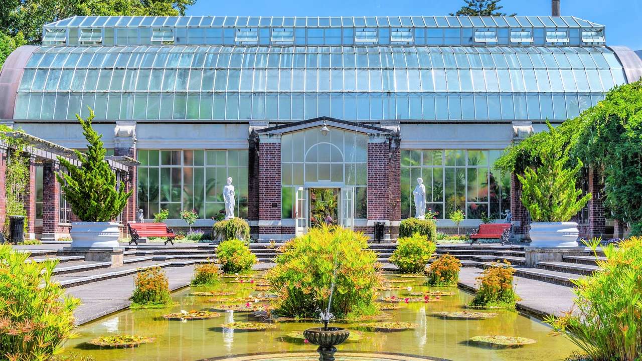 A greenhouse with a garden with a water fountain in front