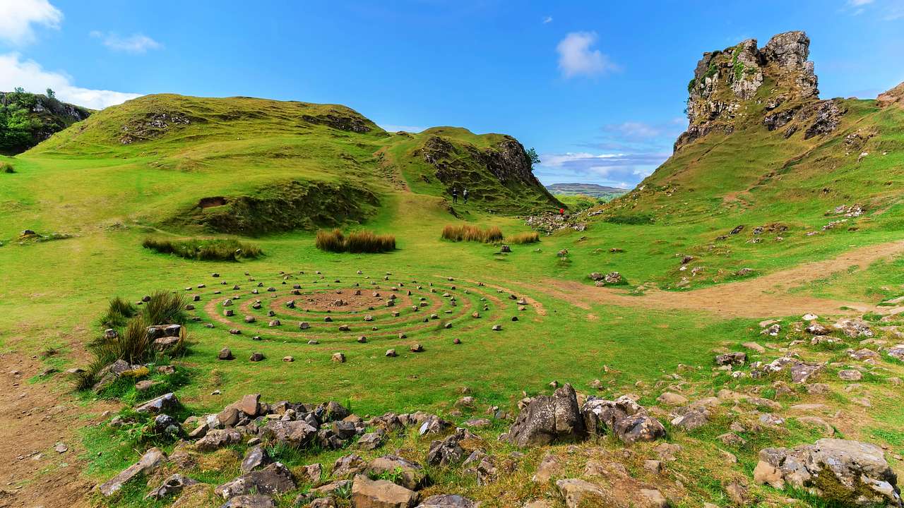 A lush valley with a small rocky hill and rocks in a concentric pattern