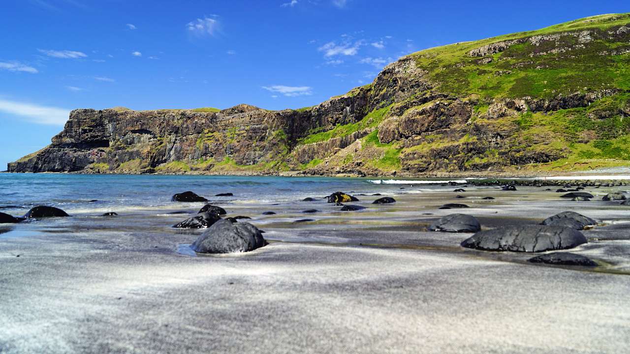 A grassy rocky sea cliff near a rocky beach shore