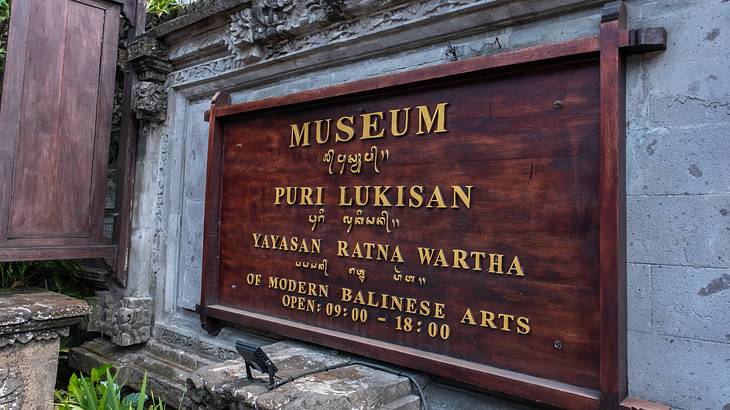 A wooden sign on a wall that says "Museum Puri Lukisan"
