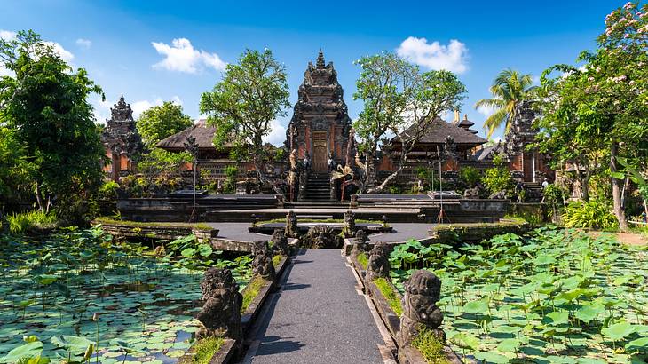A temple next to a path, greenery, and ponds with lily pads