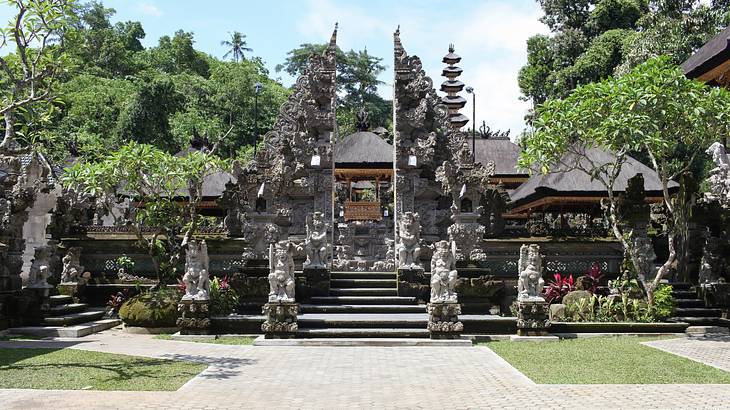 A temple with stone carvings next to a path and green trees on a clear day