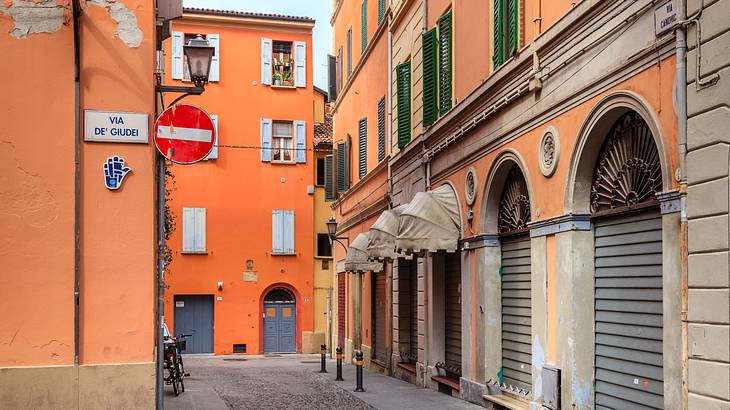 An empty paved street surrounded by orange buildings