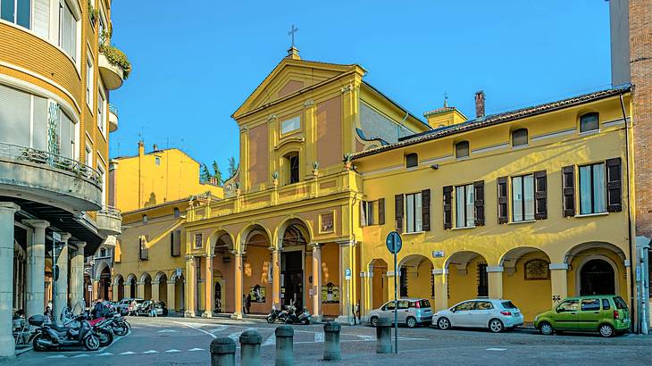 An old yellow building with vehicles in front