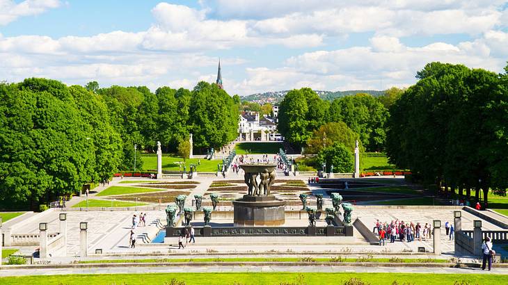 A view of a park with a fountain, paths, and lots of greenery