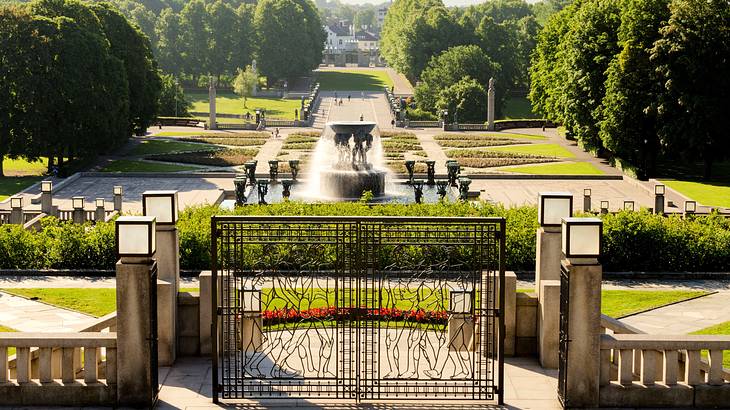 Aerial shot of a gated landscaped garden with trees, a water fountain, and sculptures