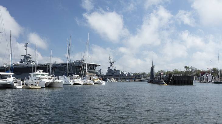 Aircraft carrier, submarine, and various boats docked in a harbor on a nice day