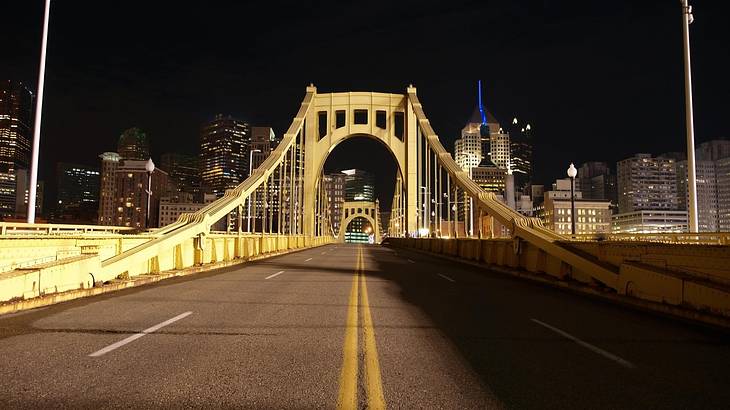 A yellow bridge with a road running through it at night