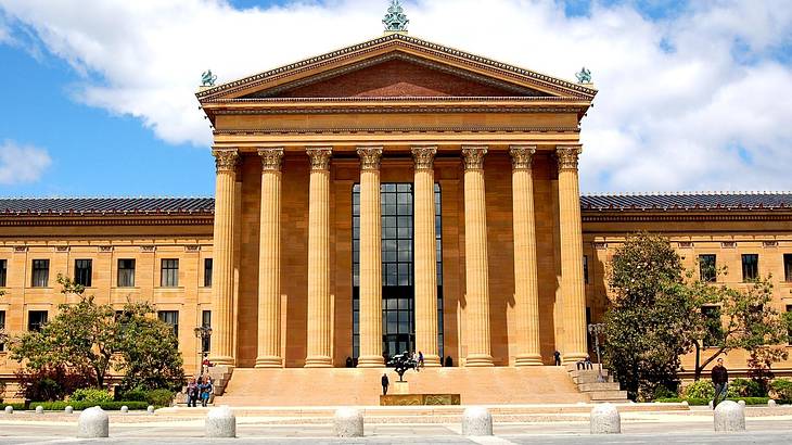 A Greek-style building with columns under a blue sky with some white clouds