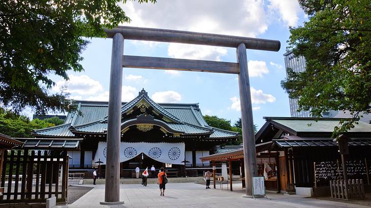 Torii gate entrance with people and a shrine in the background