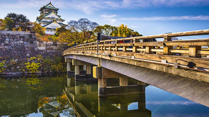 A castle at the end of a bridge over a calm river