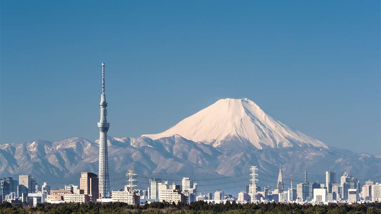 An observation tower with a view of a city skyline and a volcano in the background