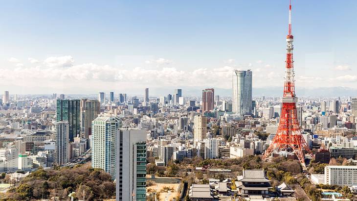 Red and white broadcasting tower overlooking a city skyline with many buildings