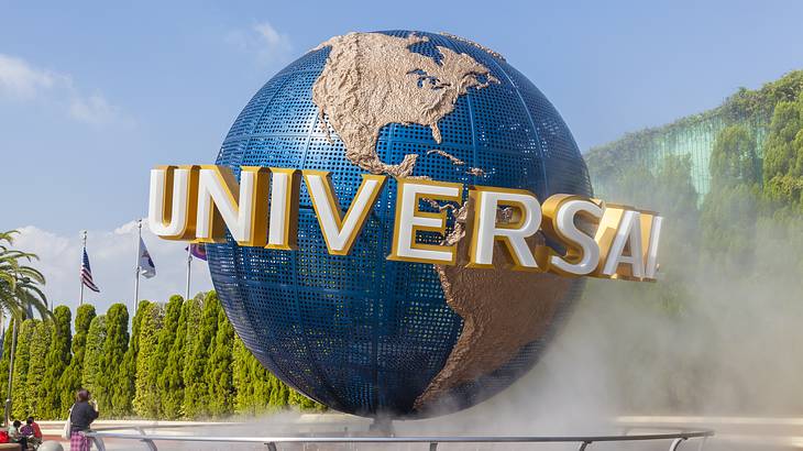 Universal Studio iconic globe, on a fenced platform, with trees around