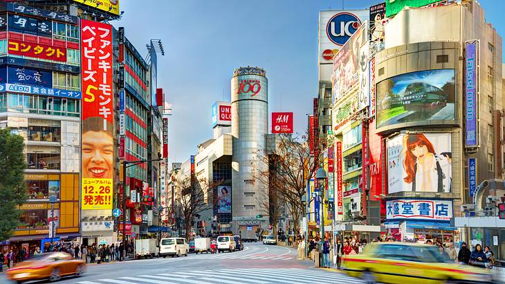 A busy crosssection at an intersection with buildings, cars, and people